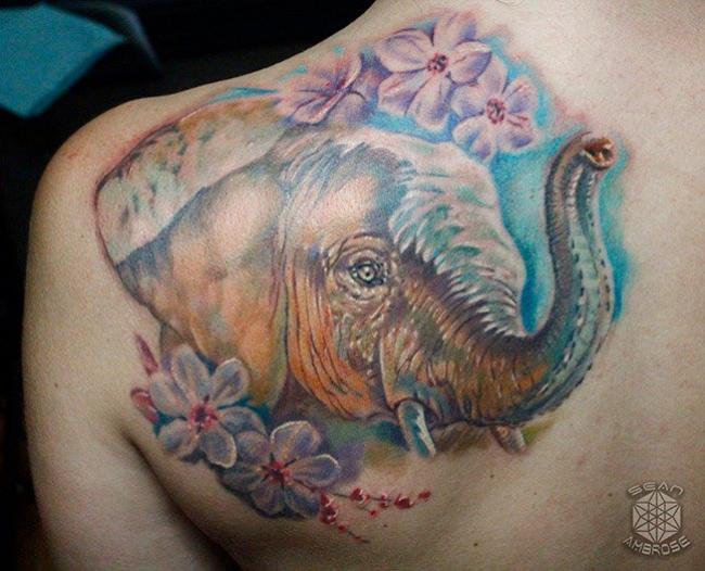 Custom realistic colorful elephant and flowers tattoo by Sean Ambrose of Arrows and Embers Tattoo in Concord, New Hampshire (NH). Sean specializes in realism and surrealism custom Tattoos. He has been awarded as the Best Tattoo Artist in NH multiple years from multiple publications, and also won handfuls of awards for his tattoos and art.