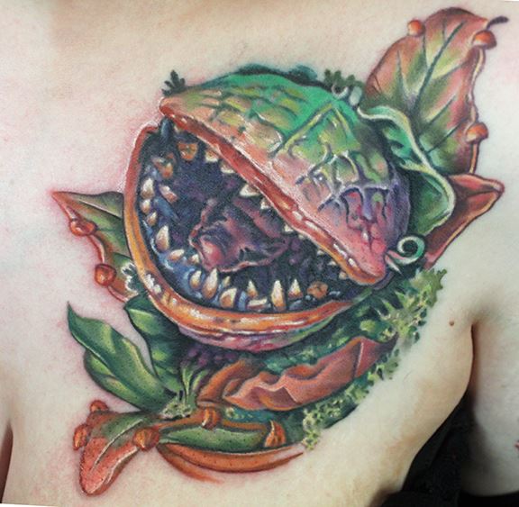 Custom colorful Audrey II portrait from Little Shop of Horrors ("FEED ME, SEYMOUR!") tattoo by Sean Ambrose of Arrows and Embers Tattoo in Concord, New Hampshire (NH). Sean specializes in realism and surrealism custom Tattoos. He has been awarded as the Best Tattoo Artist in NH multiple years from multiple publications, and also won handfuls of awards for his tattoos and art.